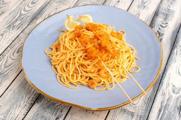 gekochte italienische Pasta lecker in blauen Platte auf grauem Holz