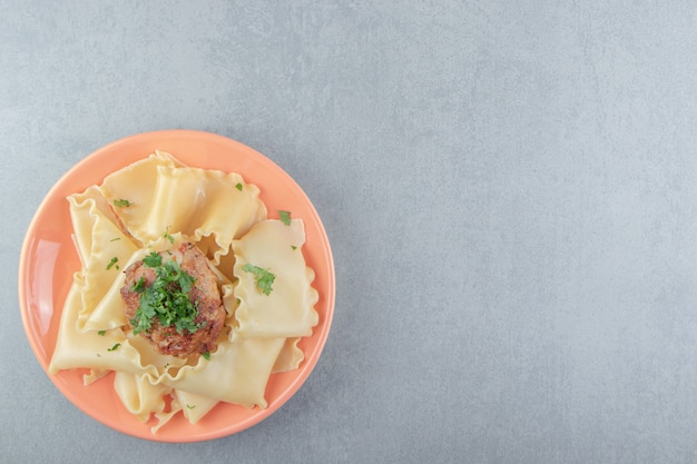 Gekochte Nudeln mit gebratenem Huhn auf orangefarbenem Teller.