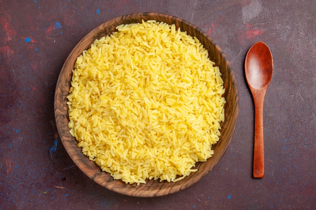 Gekochte Reis köstliche Mahlzeit der Draufsicht innerhalb der braunen Platte auf dunklem Raum