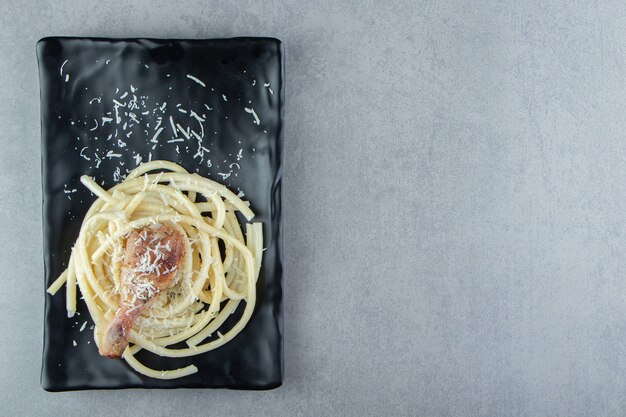 Gekochte Spaghetti-Nudeln auf schwarzem Teller.