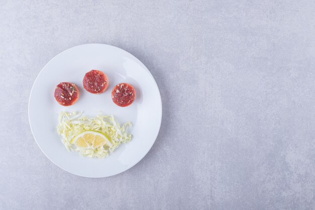 Gekochte Würste und geriebener Käse auf weißem Teller.