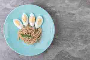 Kostenloses Foto gekochtes ei und spaghetti auf blauem teller.