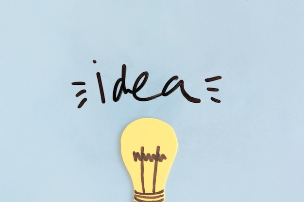 Kostenloses Foto gelbe glühlampe mit ideenwort auf blauem hintergrund