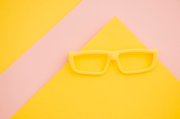 Gelbe Kinderbrillen auf rosa und gelbem Hintergrund