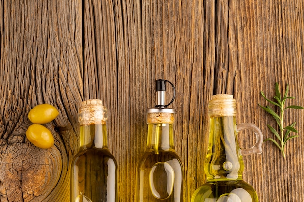 Gelbe Oliven und Ölflaschen auf hölzernem Hintergrund