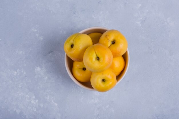 Gelbe Pfirsiche in einer weißen Keramikschale in der Mitte des Tisches