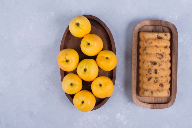 Gelbe Pfirsiche und Rollkuchen in Holzplatten in der Mitte des Tisches