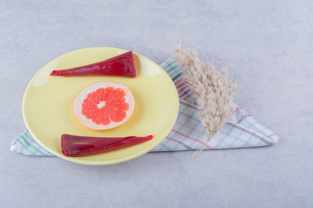 Gelbe Platte von Trockenfruchtpulpen und Grapefruit auf Steintisch.