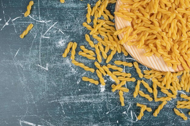 Gelbe rohe Fusilli-Nudeln auf Holzteller. Hochwertiges Foto