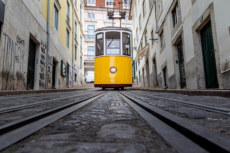 Kostenlose Foto gelbe straßenbahn fährt eine schmale gasse entlang, die von alten gebäuden umgeben ist