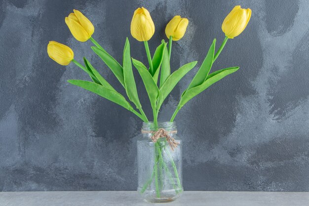 Gelbe Tulpen in einem Glas auf dem weißen Tisch.
