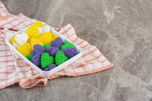 Gelbe und violette Bonbons in harter Form im weißen Teller.