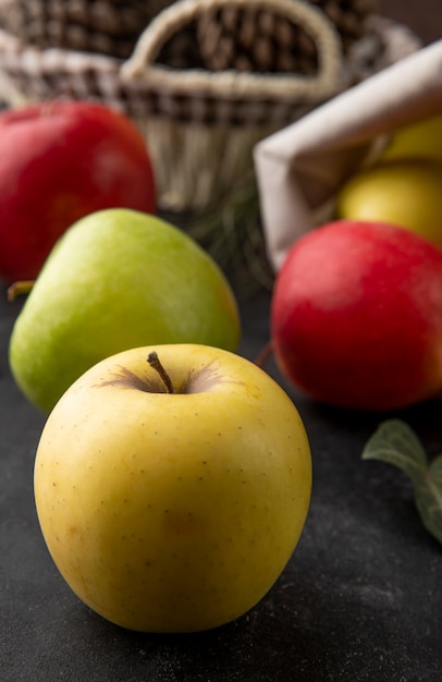 Gelber Apfel der Vorderansicht mit rotem und grünem Apfel auf einem schwarzen Tisch