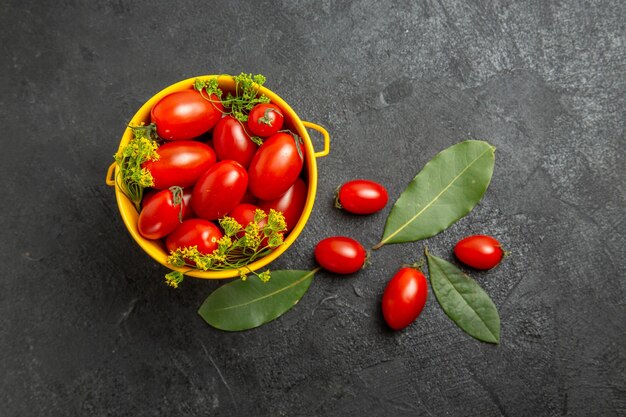 Gelber Eimer mit Kirschtomaten und Dillblumen und Lorbeerblättern von oben Draufsicht auf dem dunklen Boden mit Kopienraum