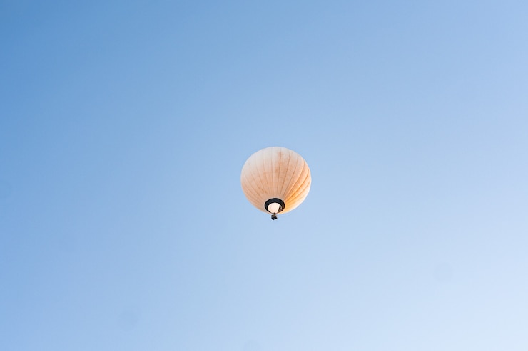 Kostenlose Foto gelber heißluftballon, der im klaren blauen himmel fliegt