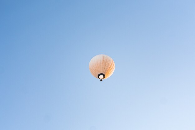 Gelber Heißluftballon, der im klaren blauen Himmel fliegt