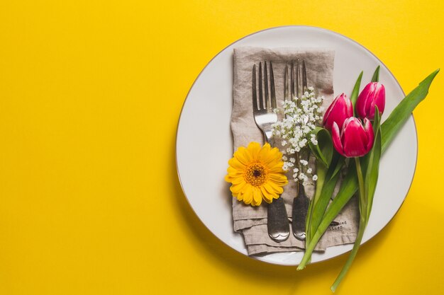 Gelber Hintergrund mit Platte und Blumenschmuck