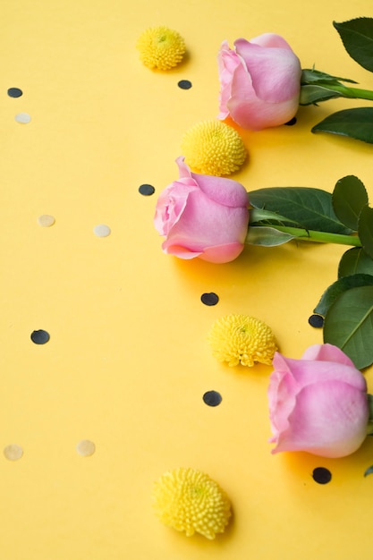 Kostenloses Foto gelber hintergrund verziert mit rosa rosen und chrysanthemenblumen