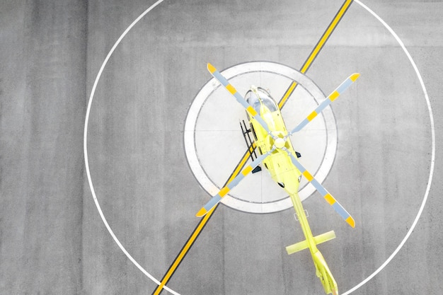 Kostenloses Foto gelber hubschrauber der draufsicht auf hubschrauberlandeplatz