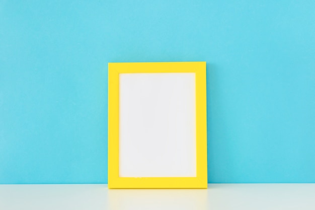 Gelber leerer Fotorahmen vor einer blauen Wand