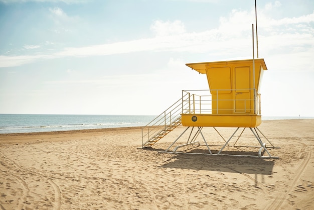 Gelber Rettungsschwimmerpfosten an einem leeren Strand