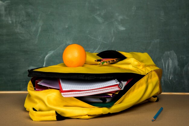 Gelber Rucksack mit Schreibheften und Orange