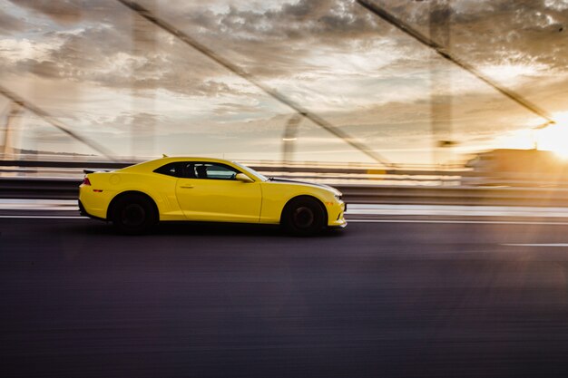 Gelbes Sportcoupé auf der Straße im Sonnenuntergang.