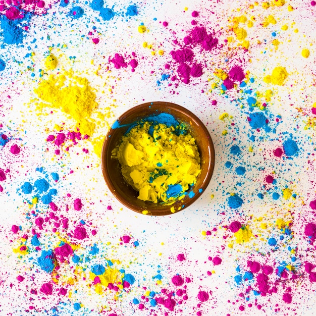 Gelbes und blaues holi Farbpulver um die Schüssel auf weißem Hintergrund