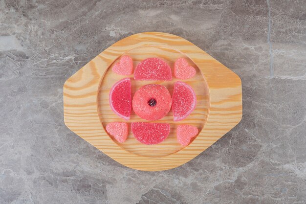 Geleebonbons um einen kleinen Donut auf einer Holzplatte auf Marmoroberfläche