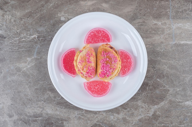 Geleebonbons und kleine Brötchen mit Nussfüllung auf einer Platte auf Marmoroberfläche