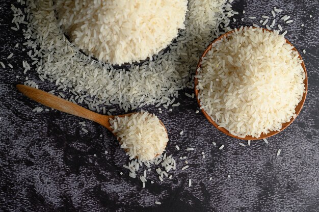 Gemahlener Reis in einer Schüssel und in einem Holzlöffel auf dem schwarzen Zementboden.
