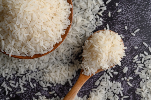 Gemahlener Reis in einer Schüssel und in einem Holzlöffel auf dem schwarzen Zementboden.