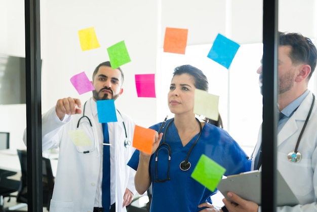 Gemeinsames Brainstorming des Ärzteausschusses im Besprechungsraum. Ärzte und eine Krankenschwester schreiben Notizen auf Haftnotizen