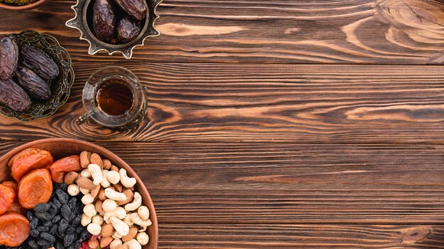 Gemischte getrocknete Früchte; Nüsse; Termine und Tee auf dem Ramadan-Festival über dem Schreibtisch aus Holz