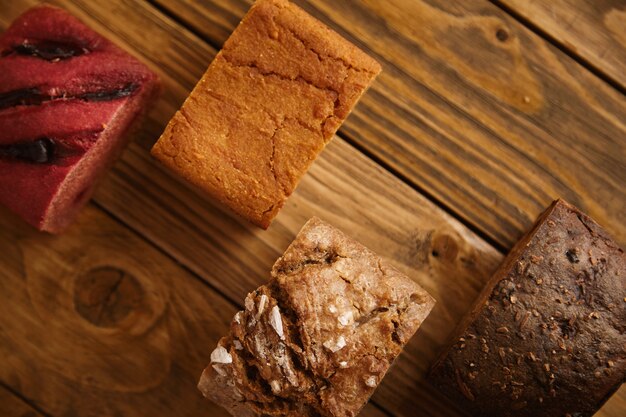 Gemischte hausgemachte Brotstücke, die auf verschiedenen Ebenen auf einem Holztisch als Muster zum Verkauf angeboten werden: