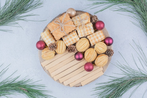 Gemischte Kekse und Weihnachtsschmuck auf Holzbrett.