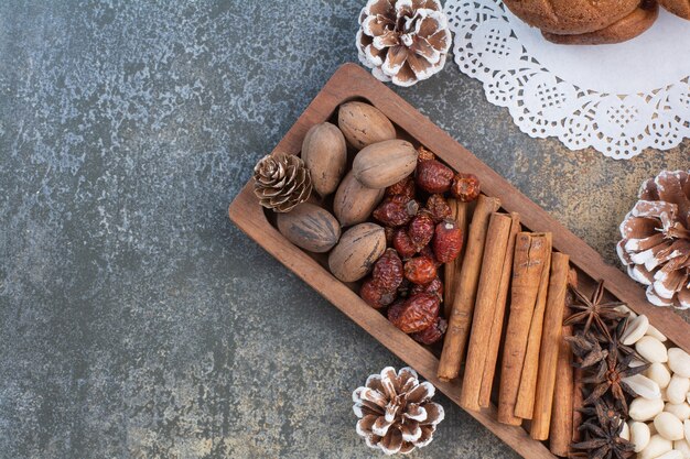 Gemischte Nüsse mit Zimtstangen und getrockneten Früchten auf Holzteller. Hochwertiges Foto