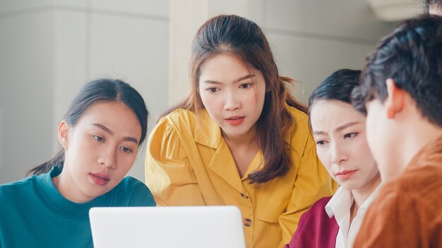 Gemischtrassige Gruppe junger kreativer Leute in der intelligenten Freizeitkleidung, die Geschäftsentwirkungs-Besprechungsideen-Entwurfsprojekt der mobilen Anwendungssoftware im modernen Büro bespricht. Teamwork-Konzept für Mitarbeiter.