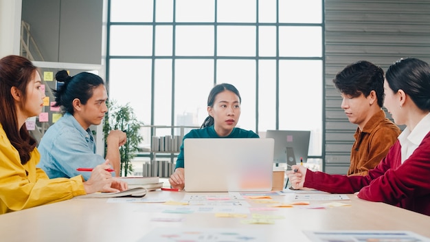 Gemischtrassige Gruppe junger kreativer Leute in der intelligenten Freizeitkleidung, die Geschäftsentwirkungs-Besprechungsideen-Entwurfsprojekt der mobilen Anwendungssoftware im modernen Büro bespricht. Teamwork-Konzept für Mitarbeiter.