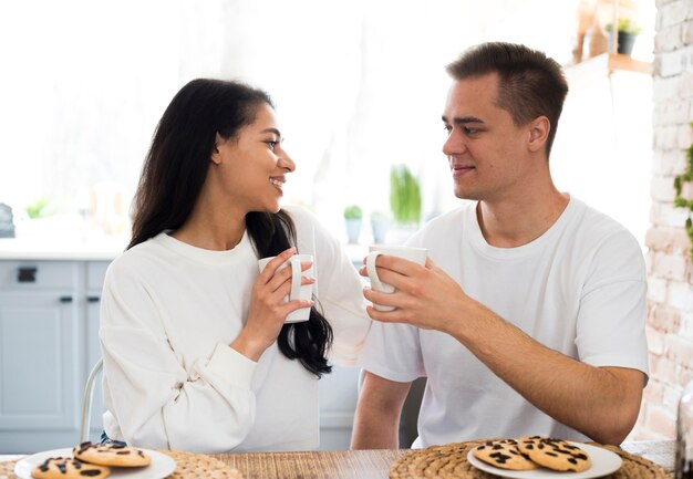 Gemischtrassige Paare, die zu Hause von der Schale trinken