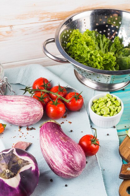 Gemüse; Gewürze und Sieb auf Tischdecke über dem Holztisch