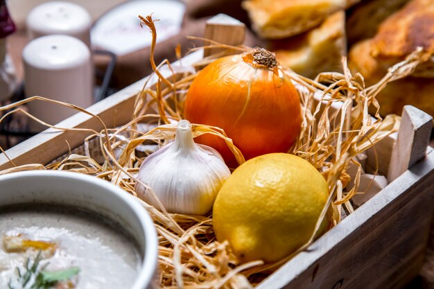 Gemüse in Holzkiste Zwiebel Knoblauch Zitrone Seitenansicht