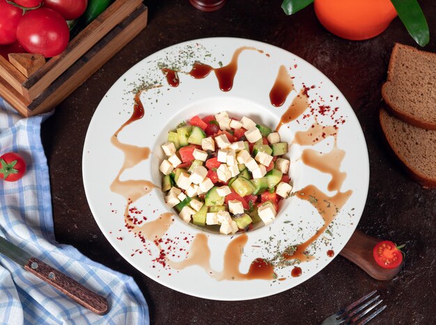 Gemüse, Tomaten, Gurken, Roka-Salat. Salat mit Sumakh und Zitrone auf dem Küchentisch in weißen Teller