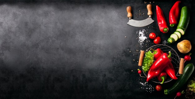 Gemüse und ein italienisches Messer auf der linken Seite von einem schwarzen Tisch