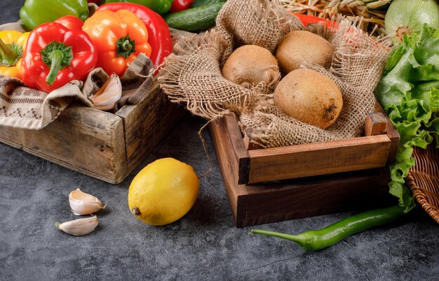 Gemüse und Kiwis in einem Holztablett mit Zitrone und Knoblauch.