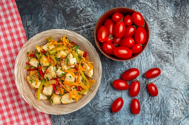 Gemüsehühnchensalat von oben mit Tomaten auf dem hellen Schreibtisch