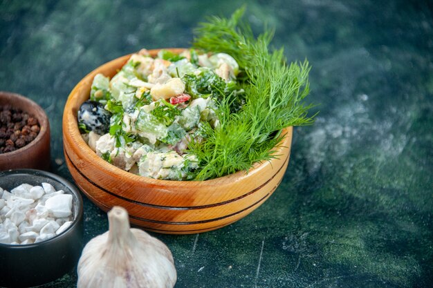 Gemüsesalat aus der Nähe mit Mayyonaise und Gemüse in einem kleinen Topf auf dunklem Hintergrund