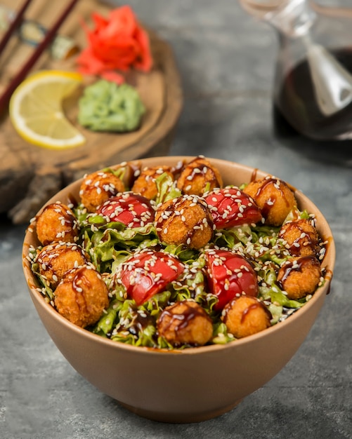 Gemüsesalat mit Fleischklöschen, Tomate und Kräutern innerhalb der Bambusschüssel.