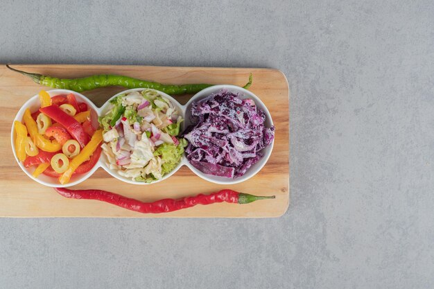 Gemüsesalat mit gemischten zutaten auf einem holzbrett.