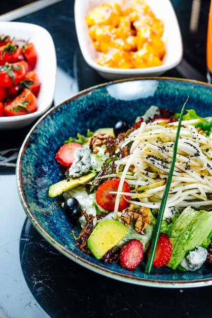 Gemüsesalat von der Seite mit Früchten Erdbeeren und Trauben in einem Teller